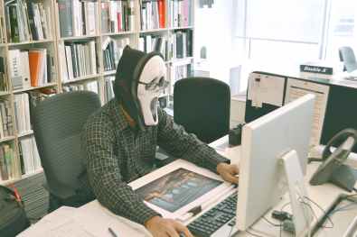 person wearing scream mask and black dress shirt while facing computer table during daytime